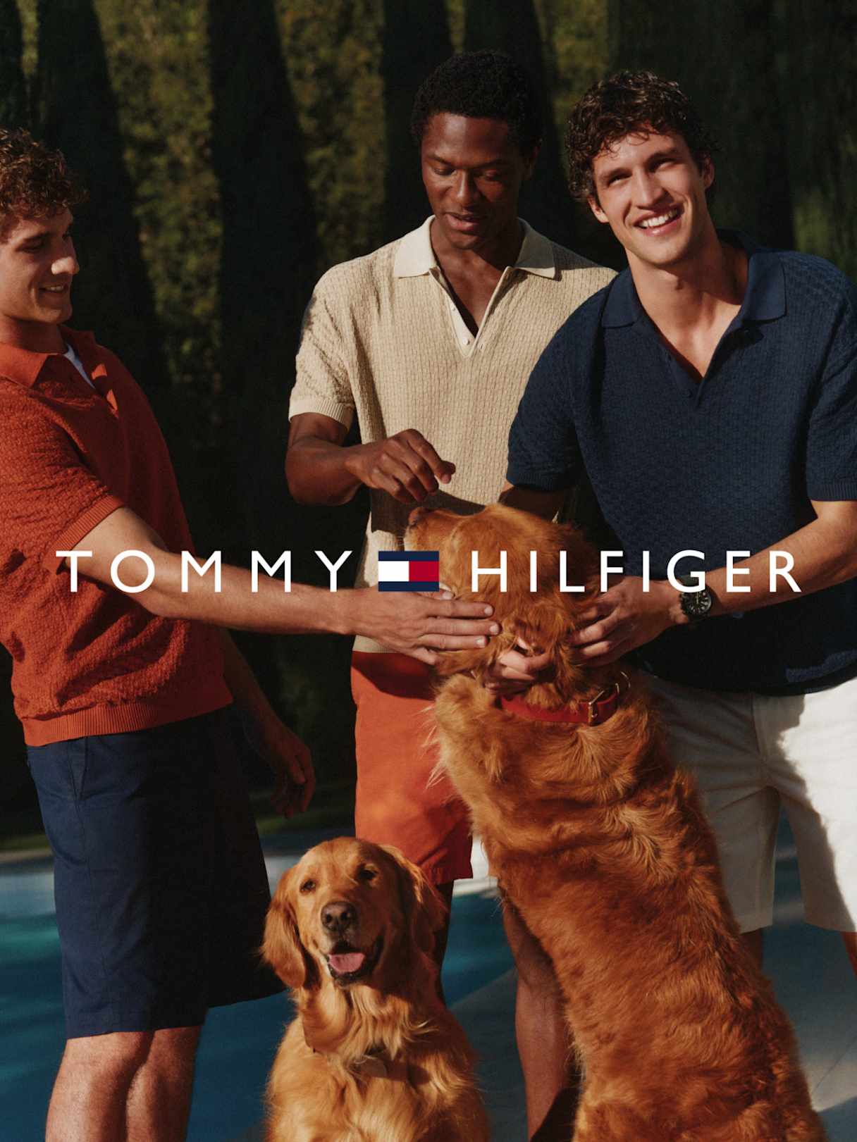 Mehrere Personen in Poloshirts spielen mit zwei Hunden am Pool, „Tommy Hilfiger“ im Vordergrund.