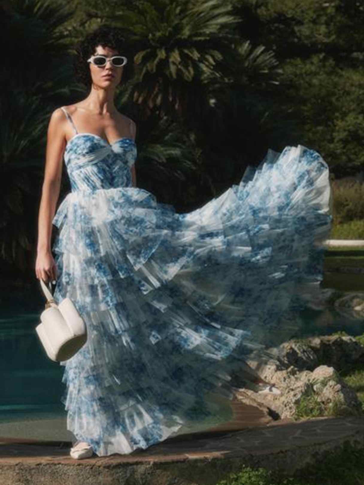 Hellblaues, bodenlanges Kleid mit feinem Muster. Figurbetontes, ärmelloses Oberteil und weit schwingender Rock aus luftigen Stofflagen. 